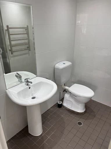 Spotless bathroom with white pedestal sink and toilet after an end-of-lease clean