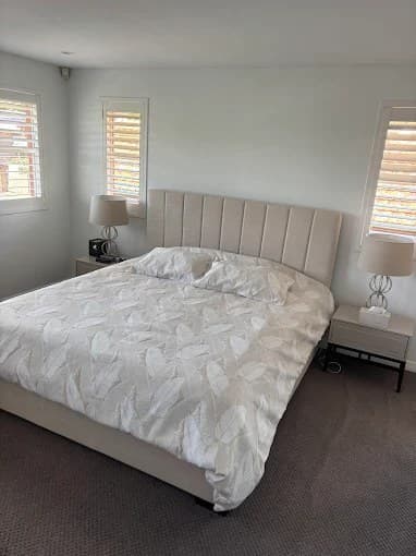 Freshly cleaned bedroom with made bed, shutters and vacuumed carpet