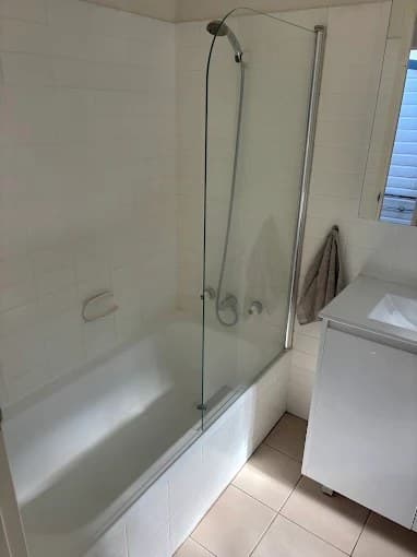 Clean bathroom with bathtub, glass shower screen and vanity