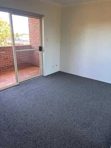 Empty room with vacuumed charcoal carpet and streak-free balcony door