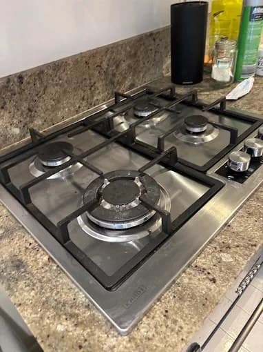 Spotless stainless-steel gas cooktop after a deep kitchen clean