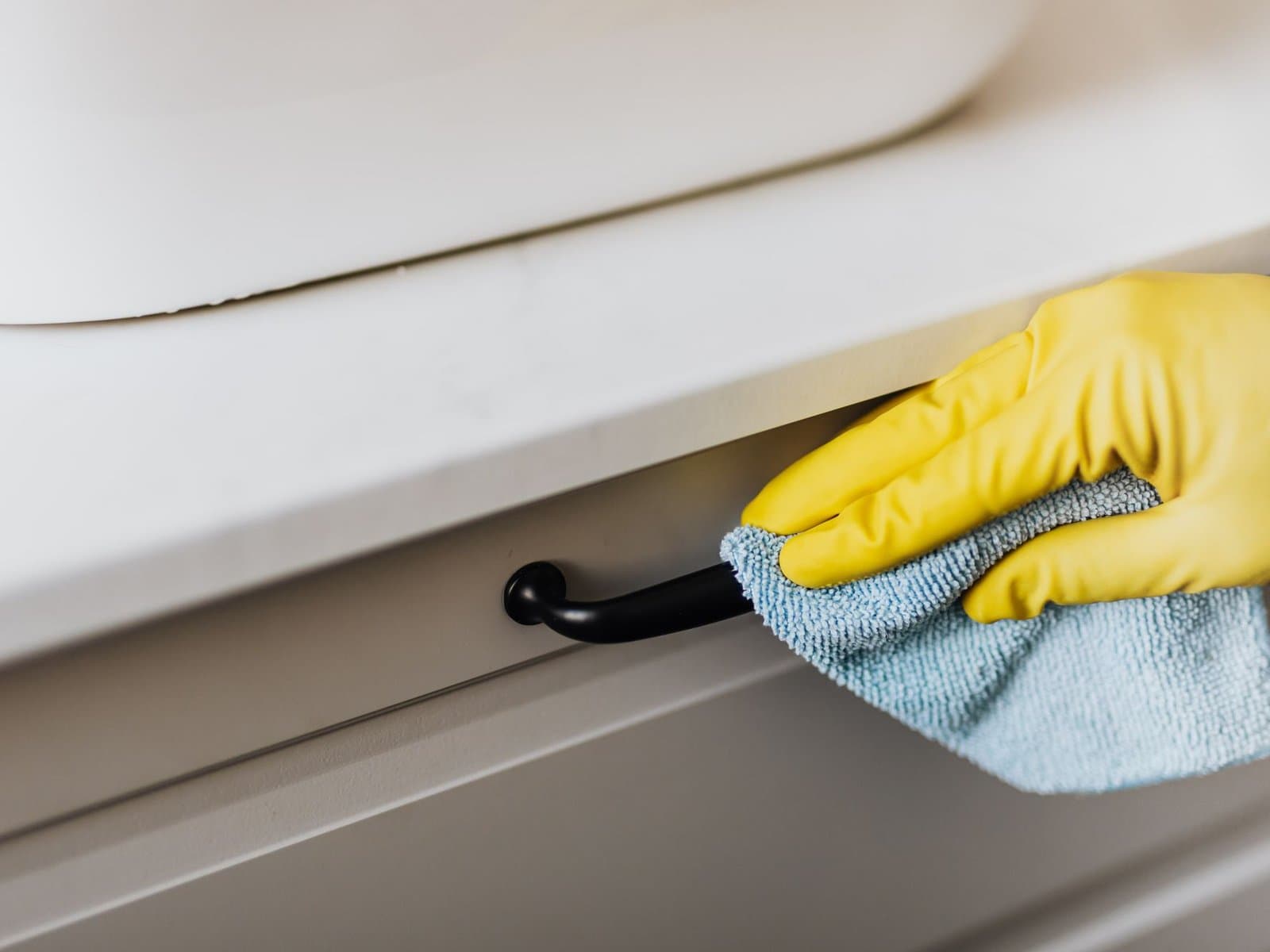 Gloved hand wiping a cabinet handle — illustrative of deep cleaning detail work in Sydney homes