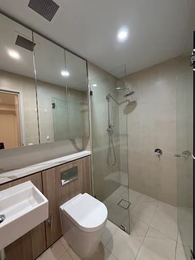 Modern bathroom with vanity, toilet and glass shower after cleaning