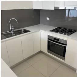 Modern kitchen with glossy white cabinets, cooktop and sink after cleaning