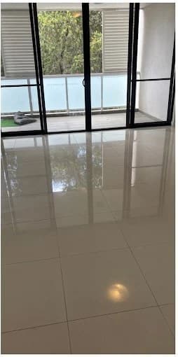 Polished tiled living-room floor reflecting balcony doors after cleaning