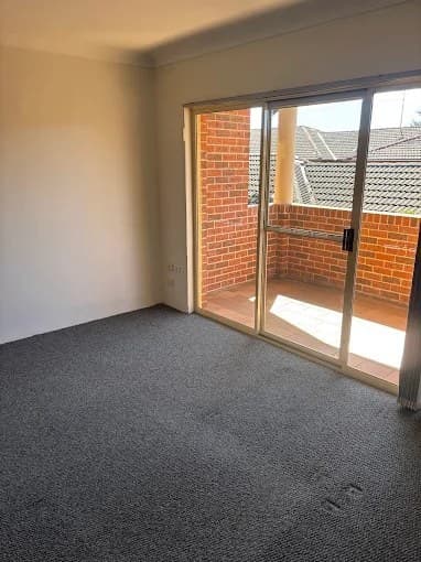Empty room with freshly vacuumed carpet opening to a brick balcony