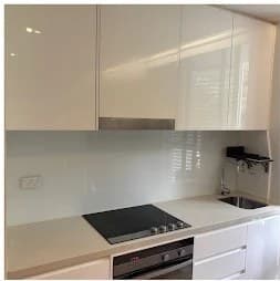 Kitchen cooktop, oven and sink with glossy white cabinets after cleaning