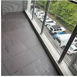 Cleaned outdoor balcony with dark tiles and clear glass railing