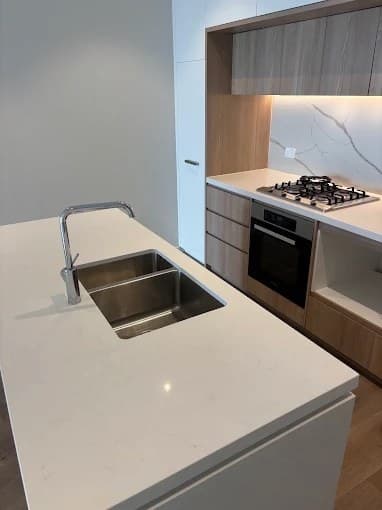 Kitchen island with double sink, gas cooktop and timber cabinets after cleaning
