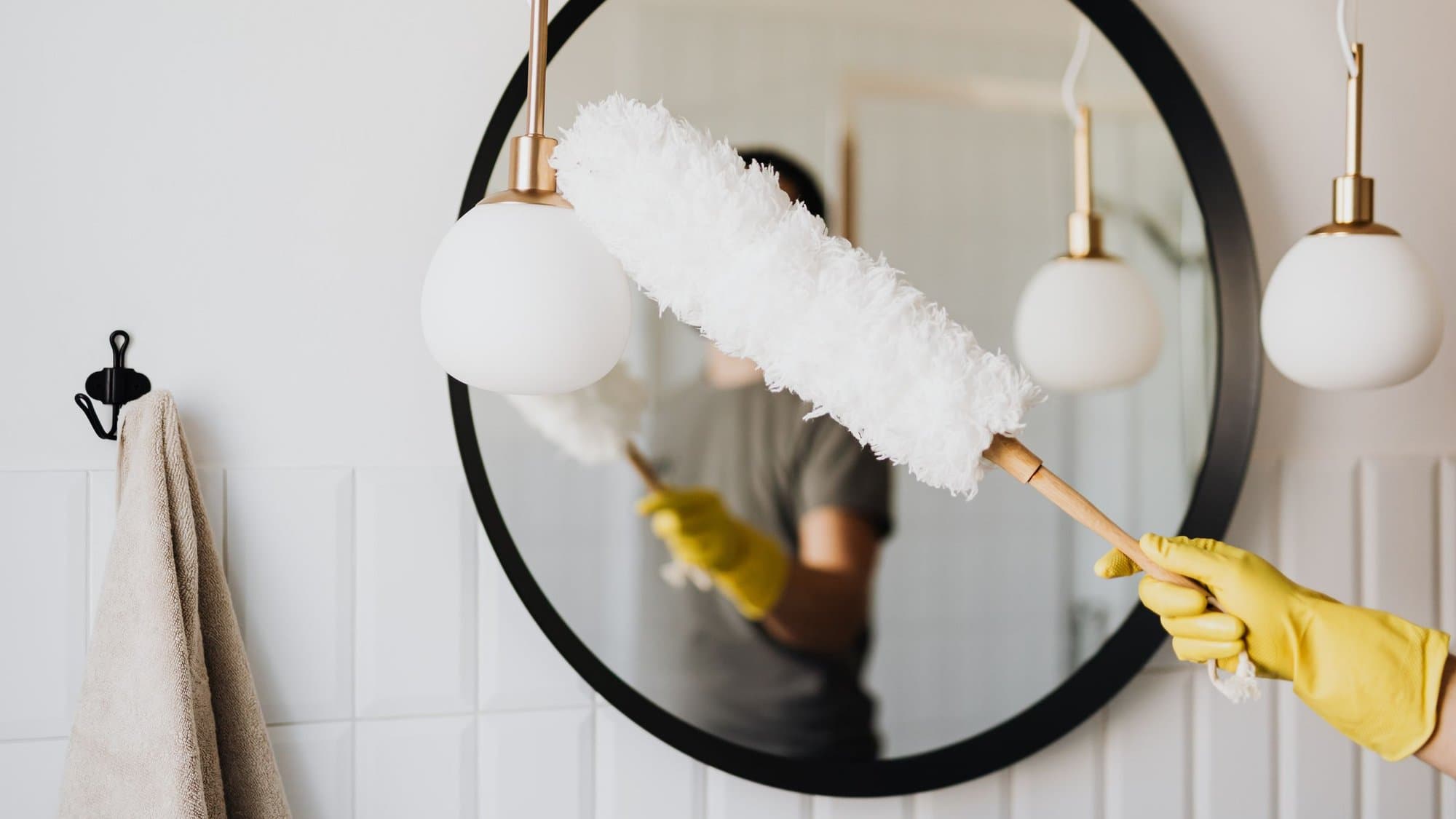 Dusting pendant lights in a bathroom — illustrative of general cleaning across Sydney